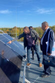 Deux hommes se tiennent devant des panneaux solaires. L'un d'eux pointe le module.