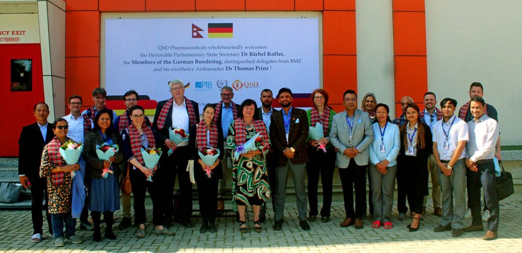 A group of people stand in front of the QbD Pharmacheuticals building.