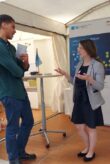 Eine Frau und ein Mann stehen sich an einem Stehtisch gegenüber und unterhalten sich.
