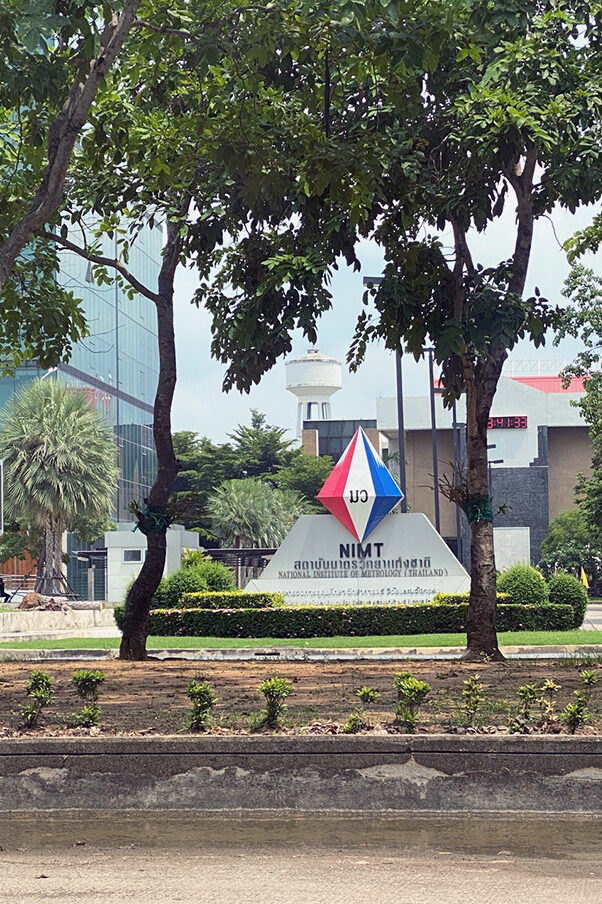 Some modern building with a glass front and a monument showing the logo of NIMT.