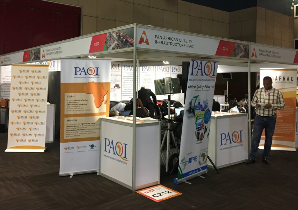 The Pan-African Quality Infrastructure (PAQI) booth is located in an exhibition hall with numerous information offers in the form of flyers and displays.