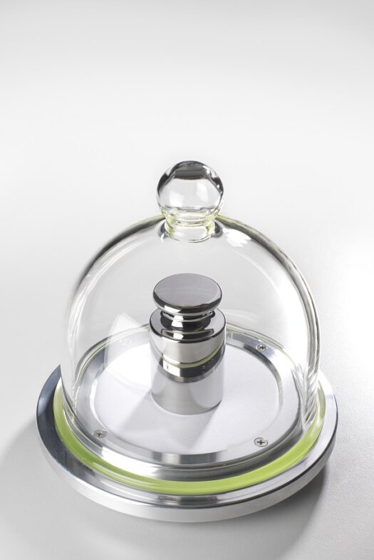 Gram weight piece under a glass bell jar.