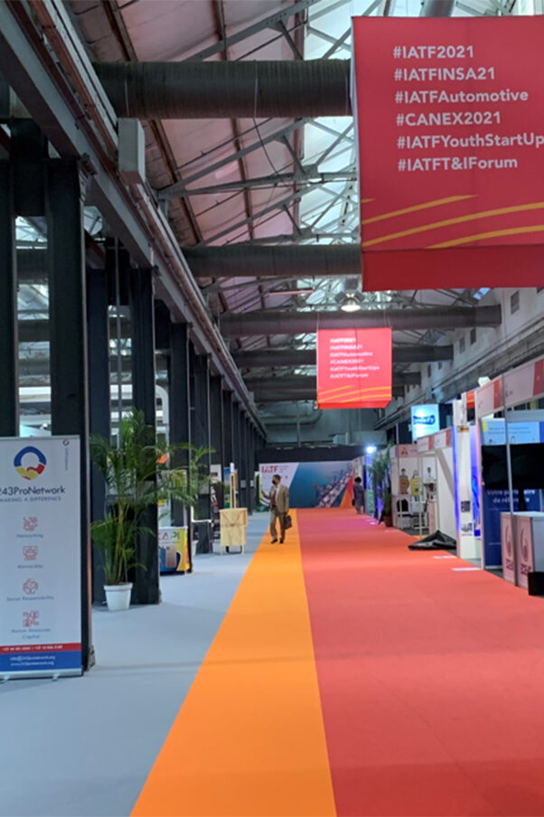 In an exhibition hall of the Intra-African Trade Fair 2021, information booths are lined up on both sides. Long banners hang from the ceiling.