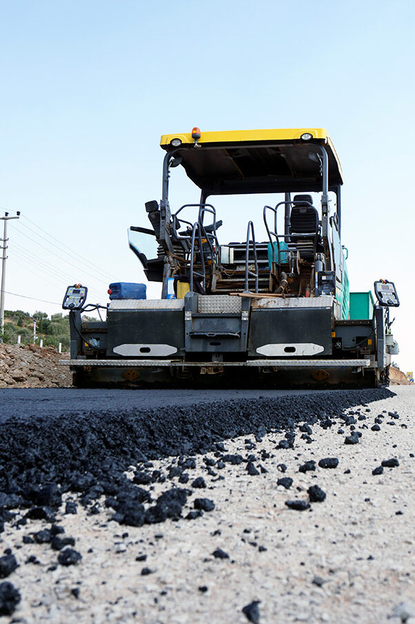 Black slag in front of an excavator.