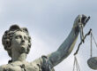 A statue of the goddess Justitia holds a pair of scales.