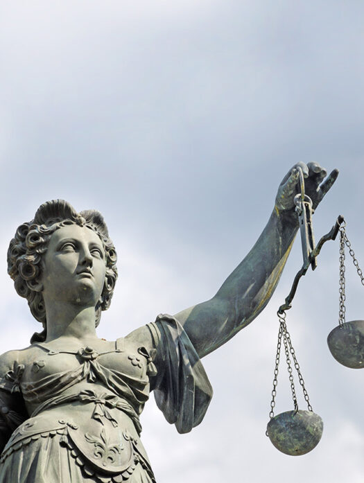 A statue of the goddess Justitia holds a pair of scales.