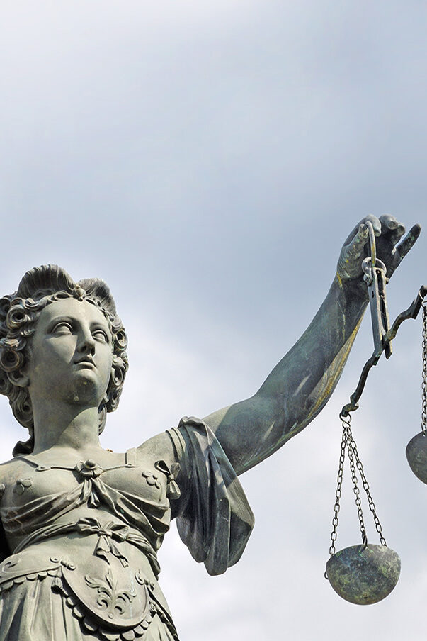 A statue of the goddess Justitia holds a pair of scales.