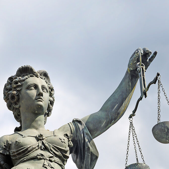 A statue of the goddess Justitia holds a pair of scales.