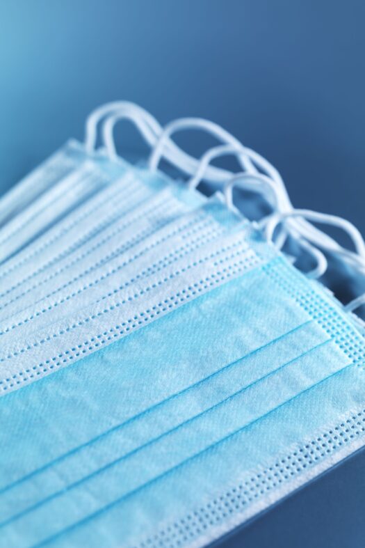 Blue disposable face masks against a dark blue background.