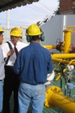 Three men wearing yellow helmets on a construction site.