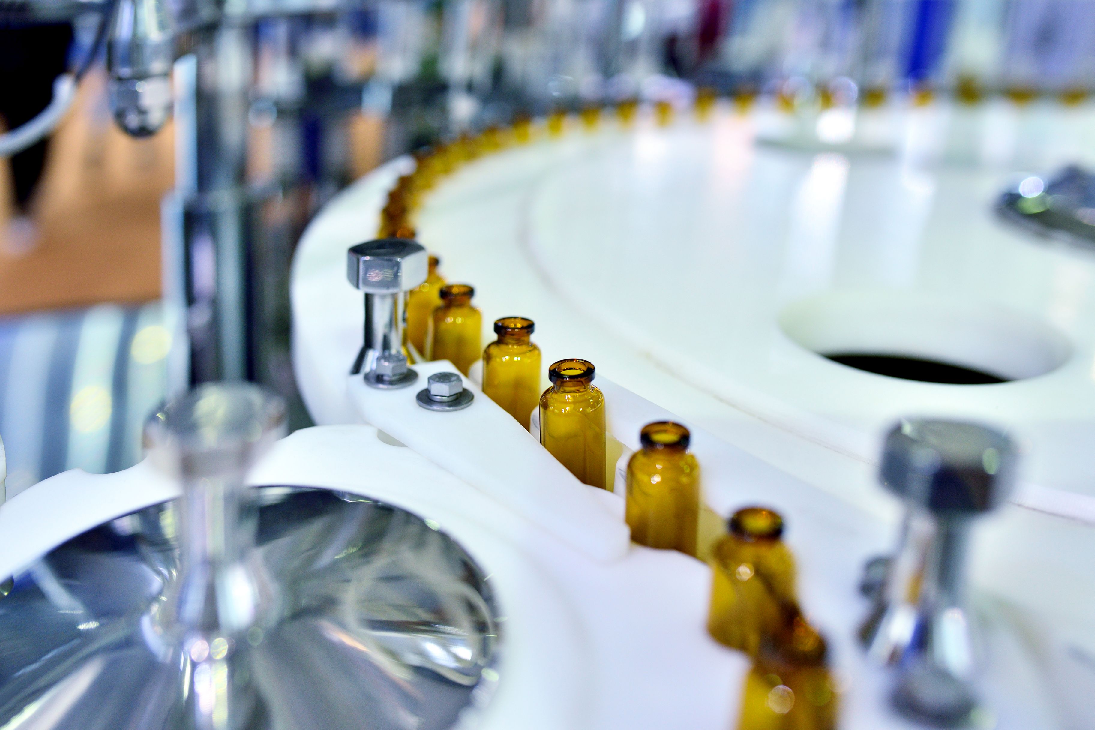 Close-up of brown glass bottles at turntable production line.