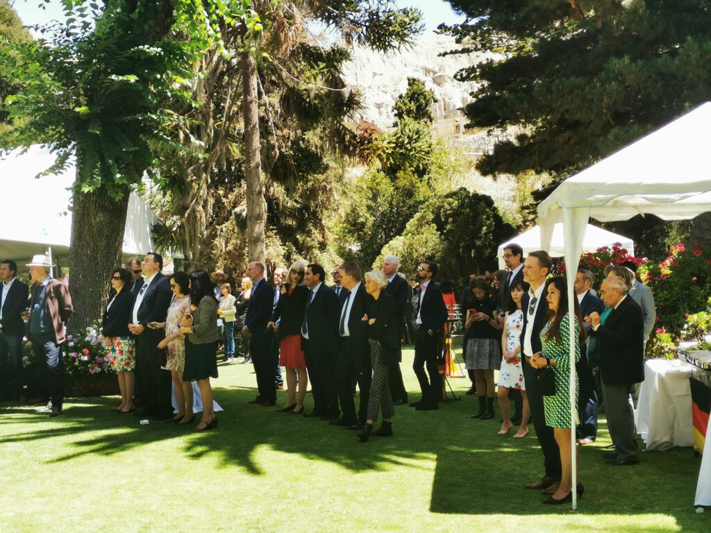 A large group of men and women stand on a green area.