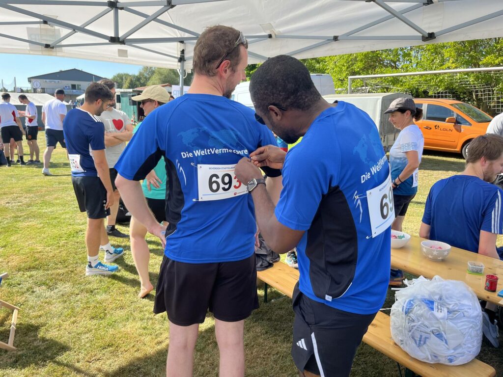 Ein Mann hilft einem anderen beim Anbringen einer Nummer auf einem T-Shirt.