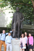 Vor einer Statue, die Werner von Siemens zeigt, stehen drei Frauen zur rechten und zwei Männer zur linken.