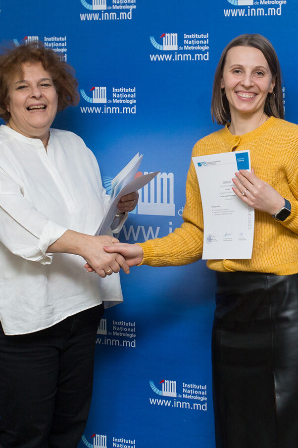 Two smiling ladies shaking hands and showing certificates