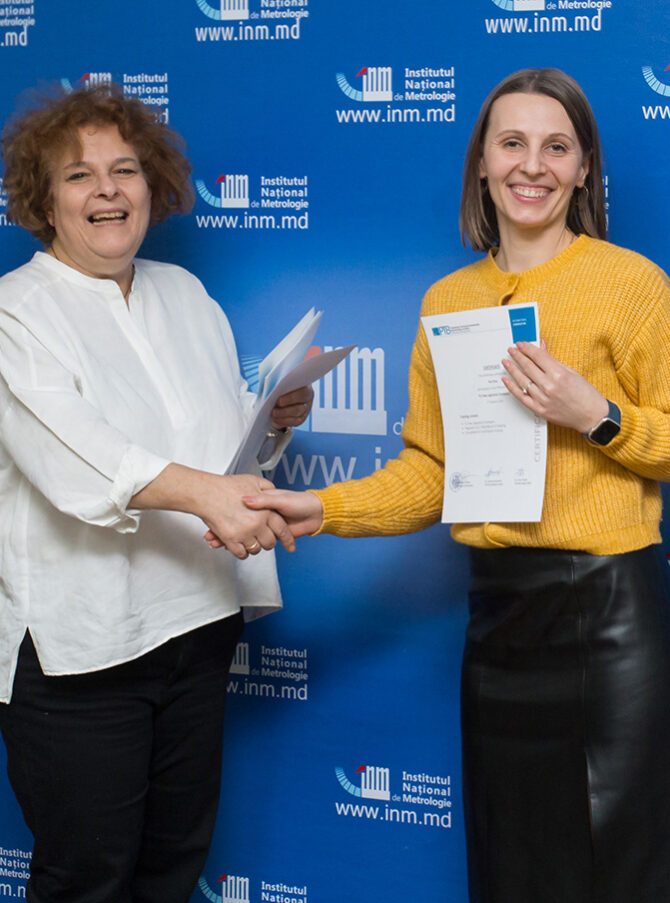 Two smiling ladies shaking hands and showing certificates