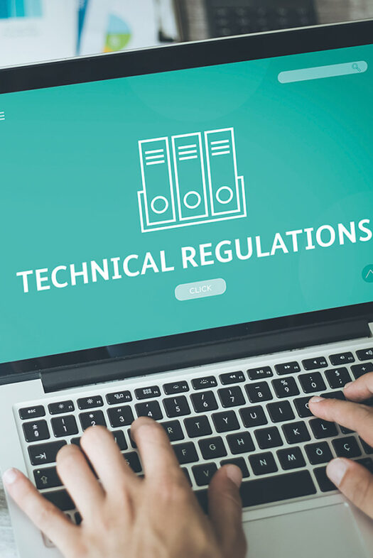 You can see hands on the keyboard of a laptop, with 'Technical Regulations' written in bold letters on the monitor.