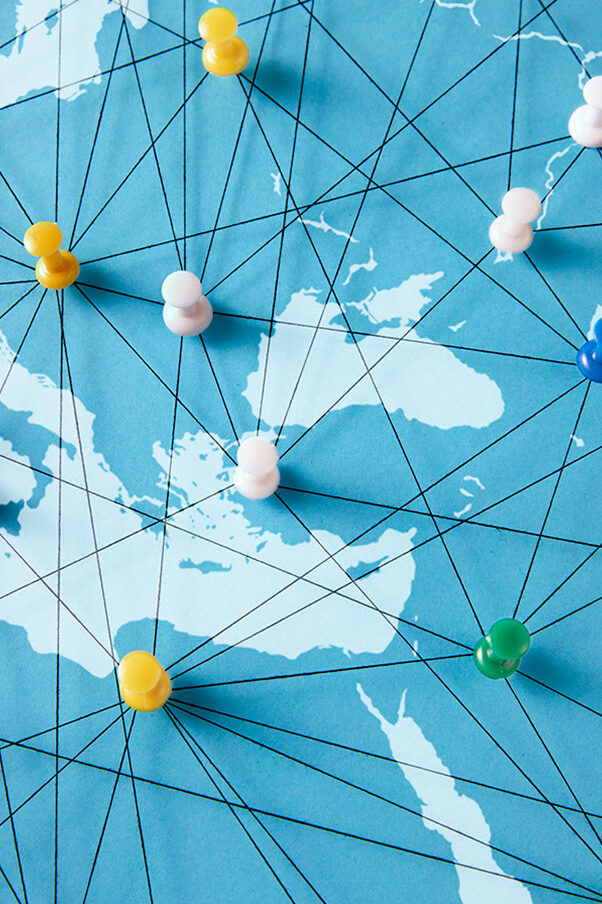 Colourful pins on a section of a world map connected with threads.