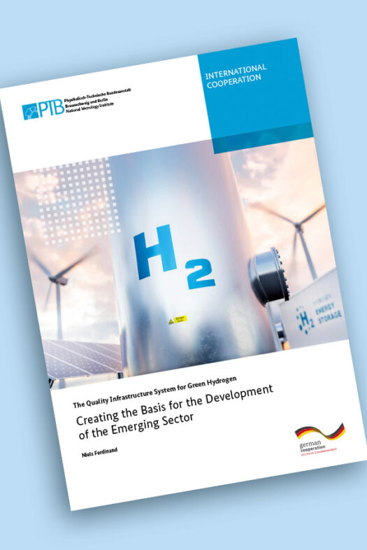 H2 is written on a metal pole. Wind turbines and solar panels can be seen in the background.