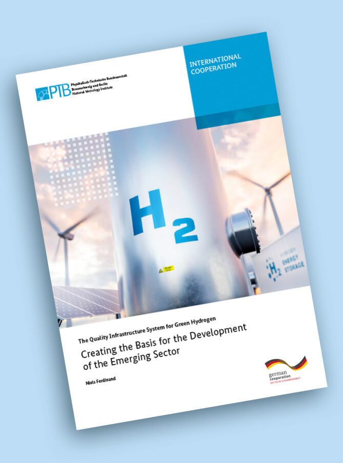 H2 is written on a metal pole. Wind turbines and solar panels can be seen in the background.