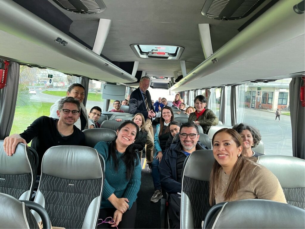 Foto tomada desde la parte delantera de un autobús. Se ven hombres y mujeres sentados en los asientos del autobús.