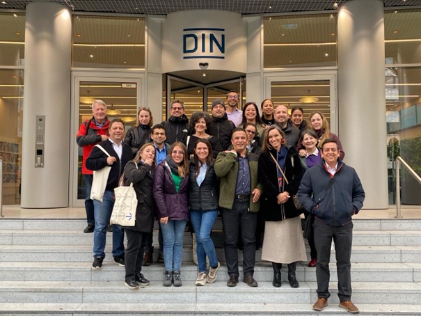 Un grupo de hombres y mujeres en la escalinata del edificio del DIN en Berlín.