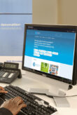 A PC monitor on a desk. The photo shows a blue website.