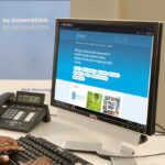 A PC monitor on a desk. The photo shows a blue website.