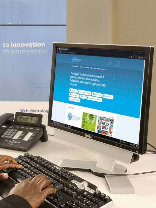 A PC monitor on a desk. The photo shows a blue website.