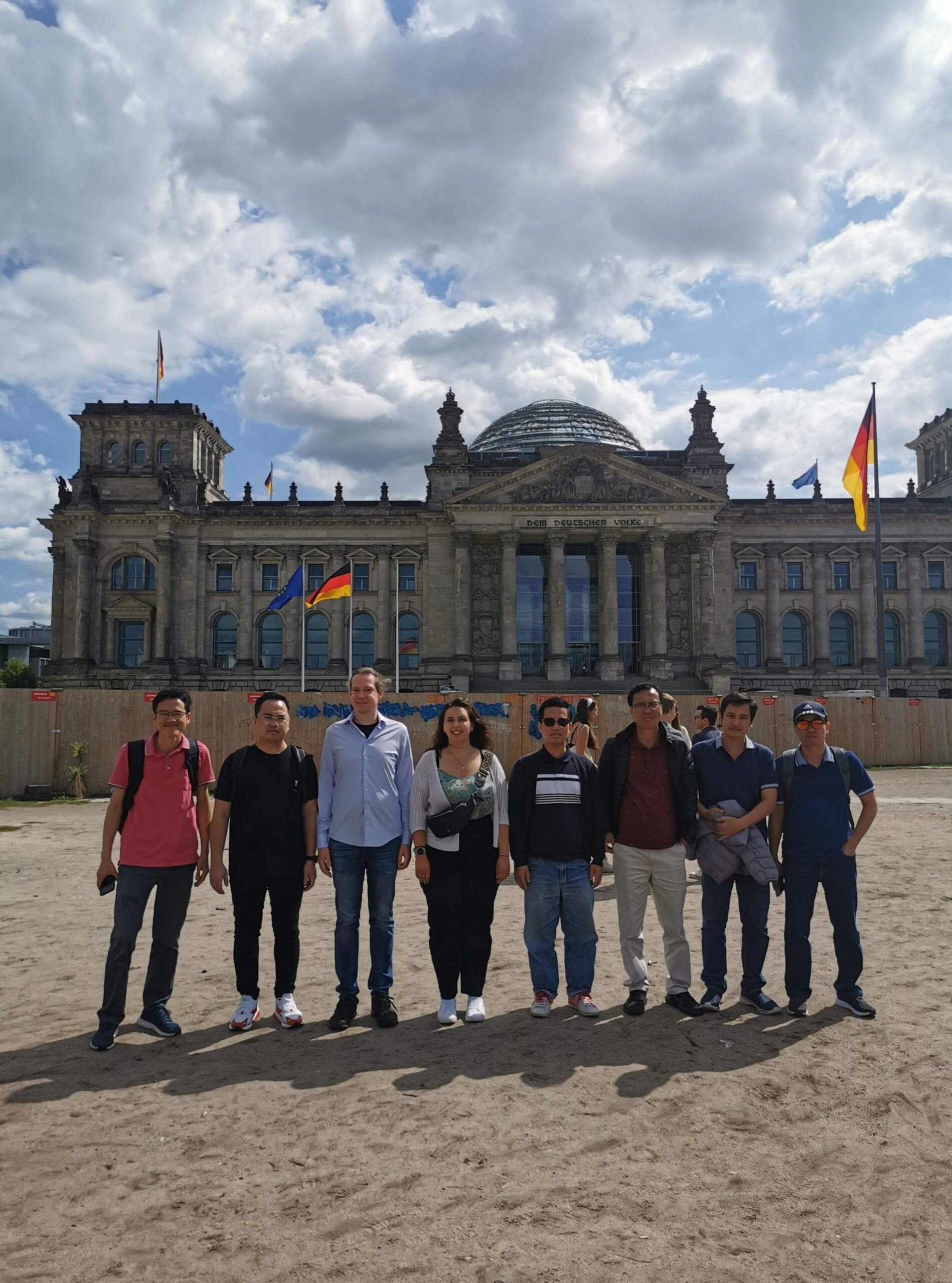 A group of people are standing in front the German Reichstag, Berlin.