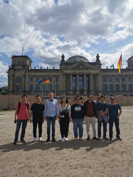 A group of people are standing in front the German Reichstag, Berlin.