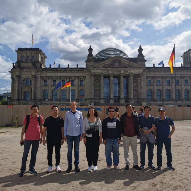 A group of people are standing in front the German Reichstag, Berlin.