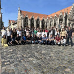 A group of people standing in front of an old Gothic building.