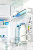 The photo shows a refrigerator with the door opened. A label mentioning the energy classification can be seen.