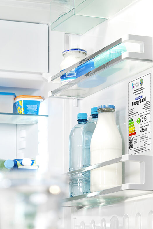 The photo shows a refrigerator with the door opened. A label mentioning the energy classification can be seen.