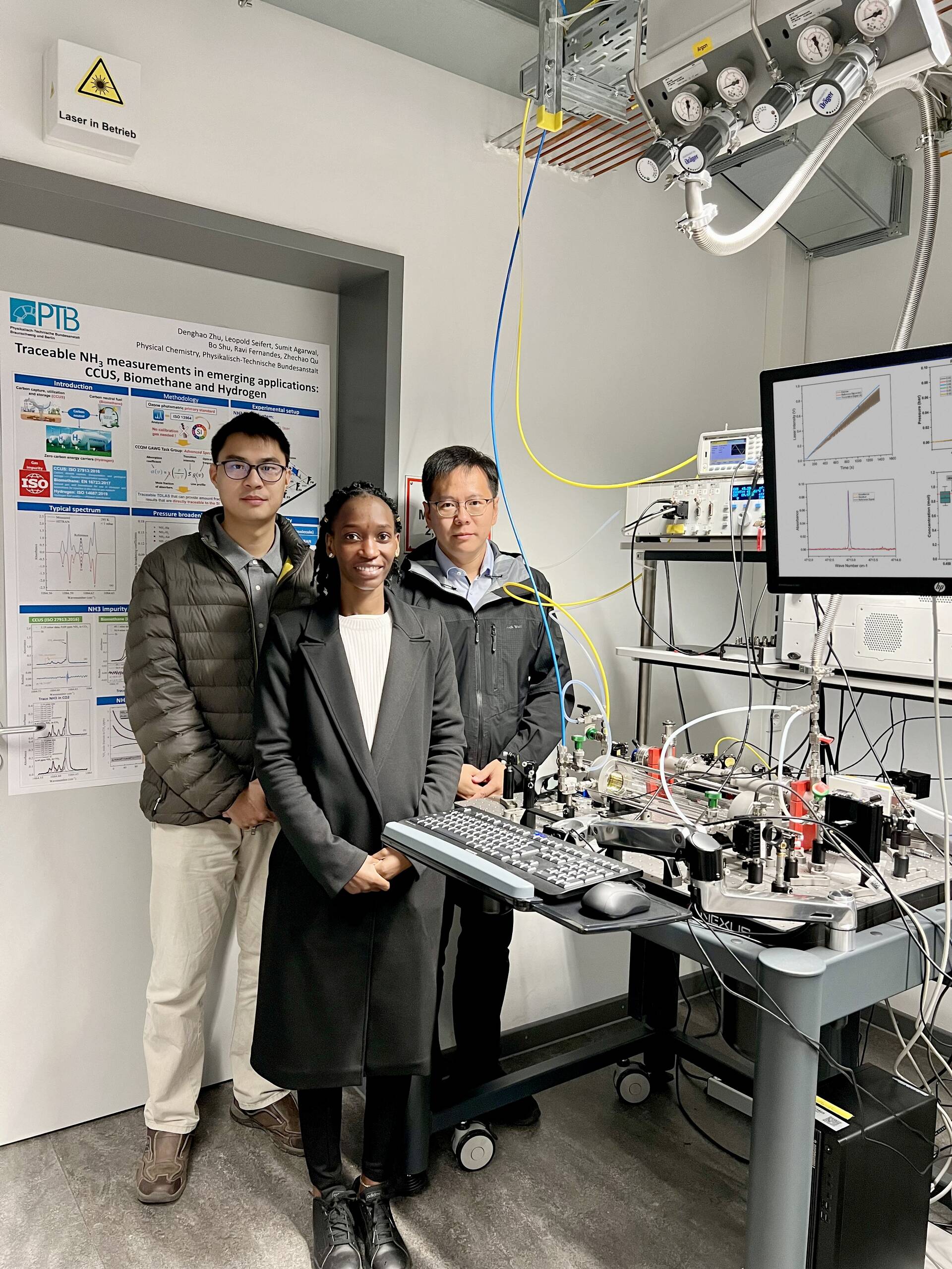 Three people standing next to high-tech equipment in a modern lab