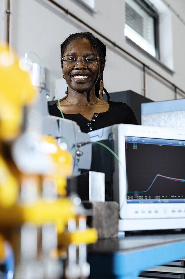 A woman standing behind research equipment for determining explosion pressure.