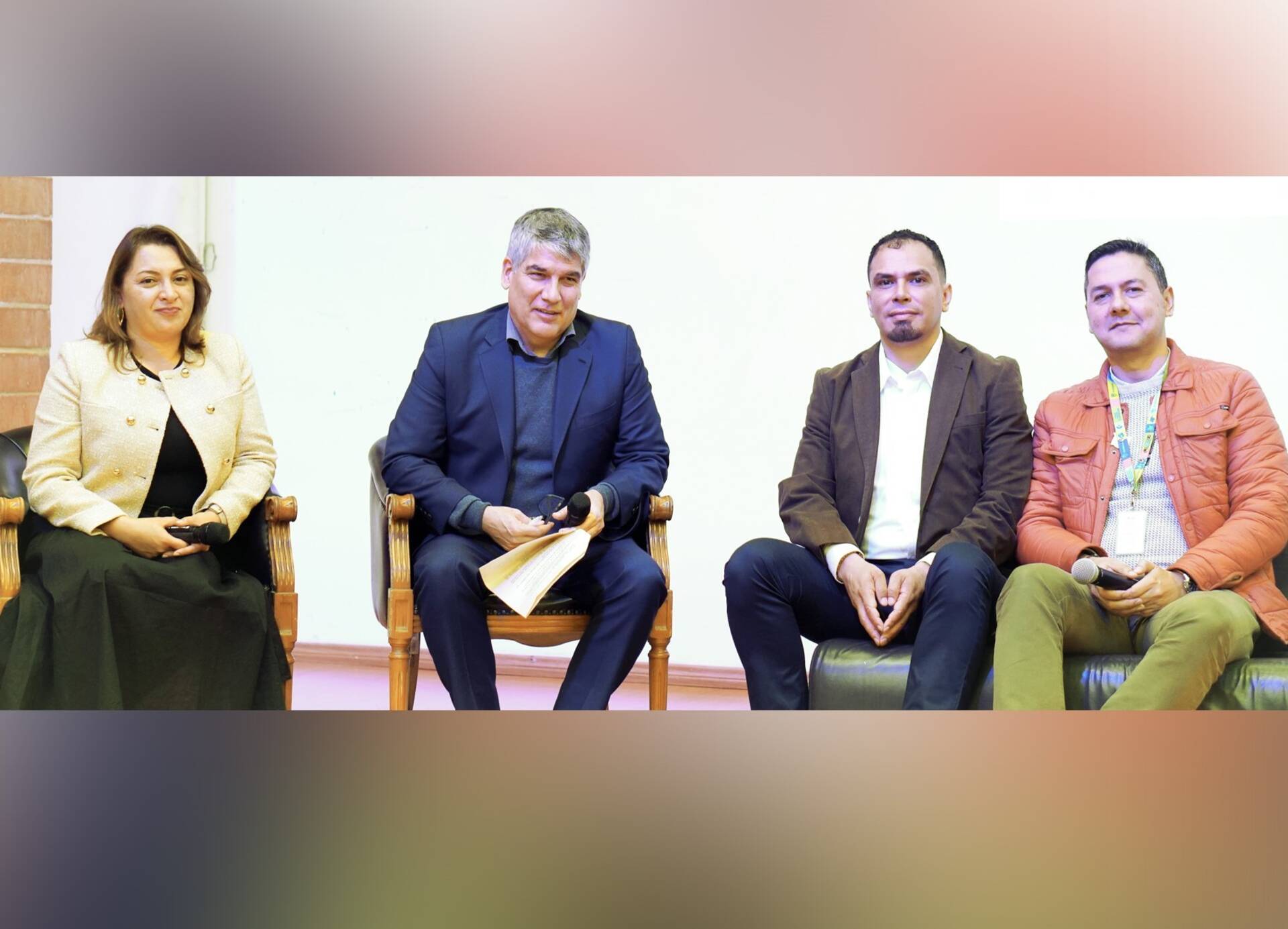 A woman and three men sitting down at an official event