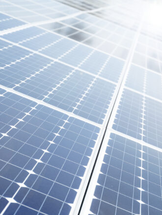 Several solar modules at an angle are in the sun and reflecting light.