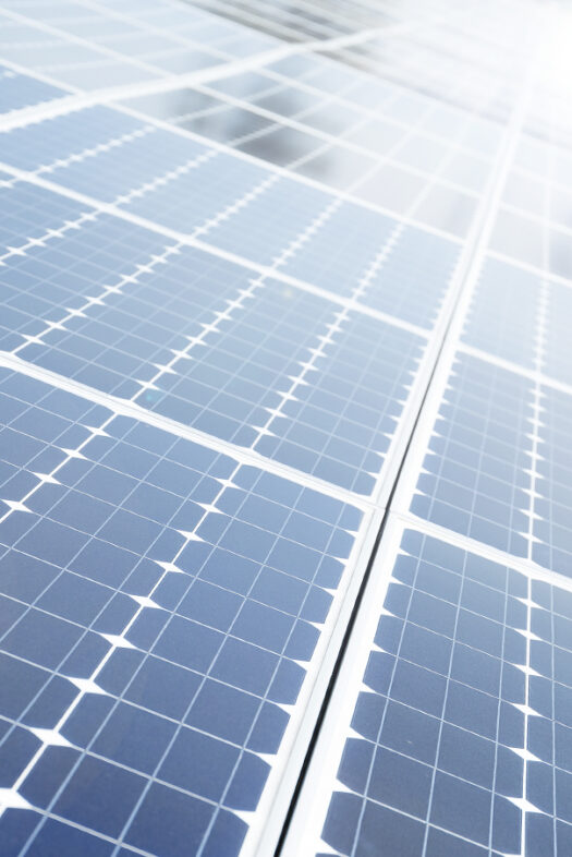 Several solar modules at an angle are in the sun and reflecting light.