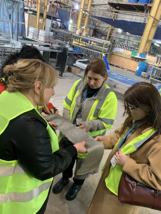 Four women are examining a swatch of fabric at Basalt Fibres Limited.