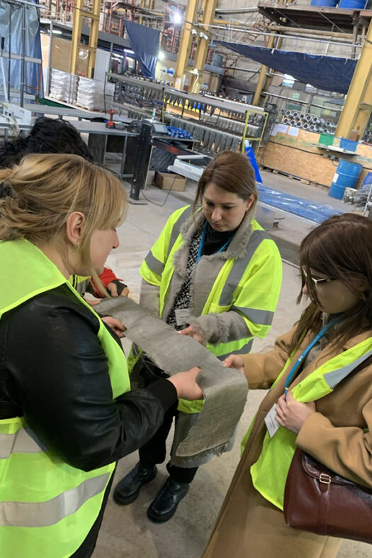 Four women are examining a swatch of fabric at Basalt Fibres Limited.